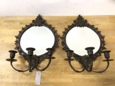 A pair of patinated metal girandole mirrors, each circular bevelled plate within frame elaborately
