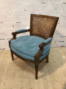 A Georgian inspired library armchair with cane back scrolled padded arms, buttoned seat cushion on