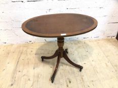 A Georgian style occasional table the cross banded oval top on turned quadraped base with down swept