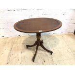 A Georgian style occasional table the cross banded oval top on turned quadraped base with down swept