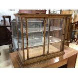An Edwardian oak display cabinet with Perspex top, sides and shelves, two sliding glass doors to