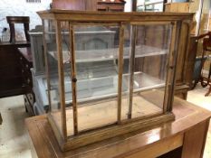 An Edwardian oak display cabinet with Perspex top, sides and shelves, two sliding glass doors to