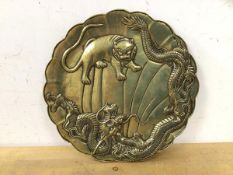A Chinese bronze plate depicting lion fighting dragon with scalloped edge (23cm d)