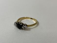 A sapphire and diamond ring marked 18k with central sapphire in claw setting flanked by two