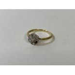 A gold cluster ring marked 18k, with five diamonds, one other stone and one stone missing, size N,