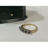 A sapphire and diamond gold ring, marked 9k, with five sapphires, separated by pairs of diamonds,