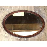 An oval wall mirror the bevelled glass within frame with moulded edge, (56cm x 81cm)