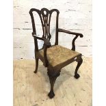 A George III mahogany open arm chair with intricately carved crest rail and pierced splat over