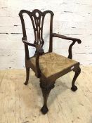 A George III mahogany open arm chair with intricately carved crest rail and pierced splat over