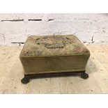 A 19thc footstool with floral upholstered top tapering base on later brass paw feet (20cm x 40cm x