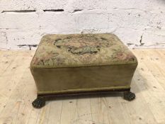 A 19thc footstool with floral upholstered top tapering base on later brass paw feet (20cm x 40cm x