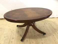 A reproduction low table the oval top on quadra pad base with down swept supports terminating in paw