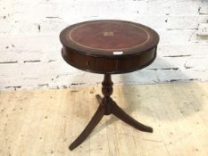 A reproduction drum table with leather top, two frieze drawers on turned down swept tripod support