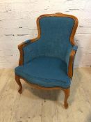 A Louis XV style bergere with teal upholstered back, arm cushions and seats, on front cabriole