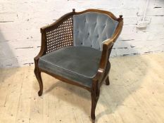 A reproduction Bergere with buttoned back, arms over caned sides, upholstered stuffed seats on
