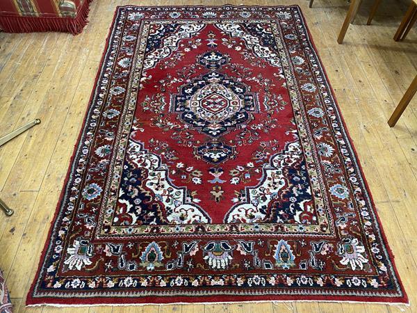 A North West Persian rug the central medallion within red field with foliate design, spandrels to