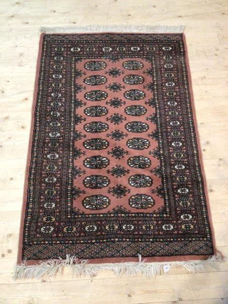 A Bokhara rug with hooked lozenges interspaced with stylised flowerhead border (142cm x 97cm)