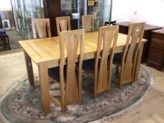 A contemporary oak extending dining table with magic leaf on straight supports, six matching