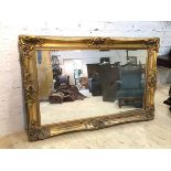 A large modern wall mirror the bevelled glass within a gilt composition frame, (123cm x 182cm)