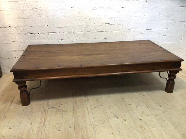 An Indonesian hardwood coffee table, metal bound, the rectangular top with moulded edge, on turned