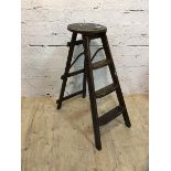 A first half 20thc elm folding step ladder with circular top with pierced handle over three