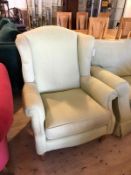 A wing back arm chair with scrolled arms seat cushion on turned supports terminating in castors,