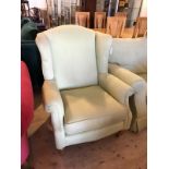 A wing back arm chair with scrolled arms seat cushion on turned supports terminating in castors,