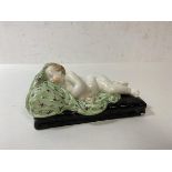 An early 19thc figure of young child asleep on blankets, (5cm h x 12cm x 6cm)
