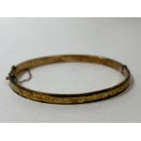 An Edwardian 9ct gold bangle, Birmingham, foliate engraving to one side, (7cm d), weighs 5.52