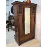 An Edwardian mahogany wardrobe the moulded cornice over a single glazed door with bevelled glass,