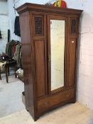 An Edwardian mahogany wardrobe the moulded cornice over a single glazed door with bevelled glass,