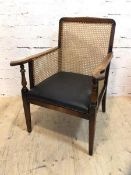 A first half 20thc mahogany library chair with caned back and sides, arms on turned supports, drop
