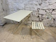 A cream painted folding table, the rectangular wooden top raised on a folding metal base, measures
