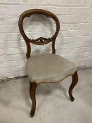 A 19thc balloon backed walnut side chair with carved surmount to back rail on cabriole supports,