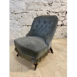 A Victorian nursing chair with buttoned back, serpentine fronted seat with fringe, on turned front