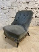 A Victorian nursing chair with buttoned back, serpentine fronted seat with fringe, on turned front