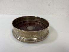 A wine coaster, the wooden base with 1969 Birmingham silver panel to centre, a silver raised edge,
