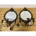 A pair of patinated metal girandole mirrors, each circular bevelled plate within frames