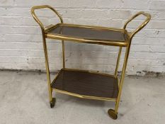 A vintage drinks trolley with brass effect exterior and wood effect tray tops, top tray removable,