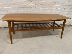 A mid century teak coffee table the top with elliptical long sides over slatted under-tier on turned