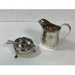 An Edwardian silver milk jug, Chester 1911, and two silver condiment spoons, Birmingham, and an