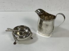 An Edwardian silver milk jug, Chester 1911, and two silver condiment spoons, Birmingham, and an