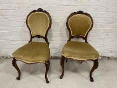 Victorian walnut his and hers side chairs with floral carved crest rails over upholstered backs