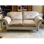 A contemporary two seat sofa upholstered in grey crushed velvet with squab cushions, raised on