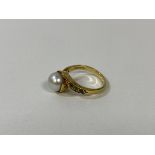 An 18 ct gold pearl and demantoid garnet ring, circa 1900, the central pearl in cross over