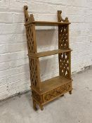 A hanging shelf with two shelves on pierced sides with drawer to base,