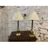 A pair of brass table lamps with column supports having corinthian style capitals, on pediment