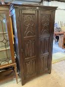 A 1920's Gothic revival wardrobe, the moulded top over two panel doors decorated with tray foils,