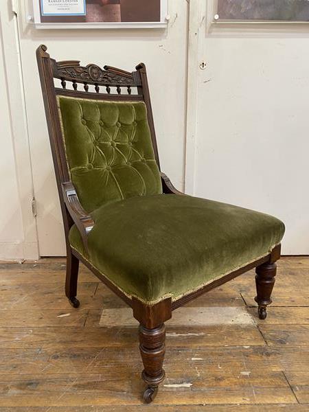 An Edwardian easy chair with carved crest rail with floral decoration