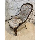 A Victorian rosewood nursing chair with later floral upholstery, with moulded top rail arms and
